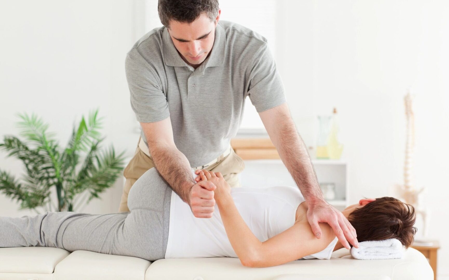 A man is stretching the woman 's arm.